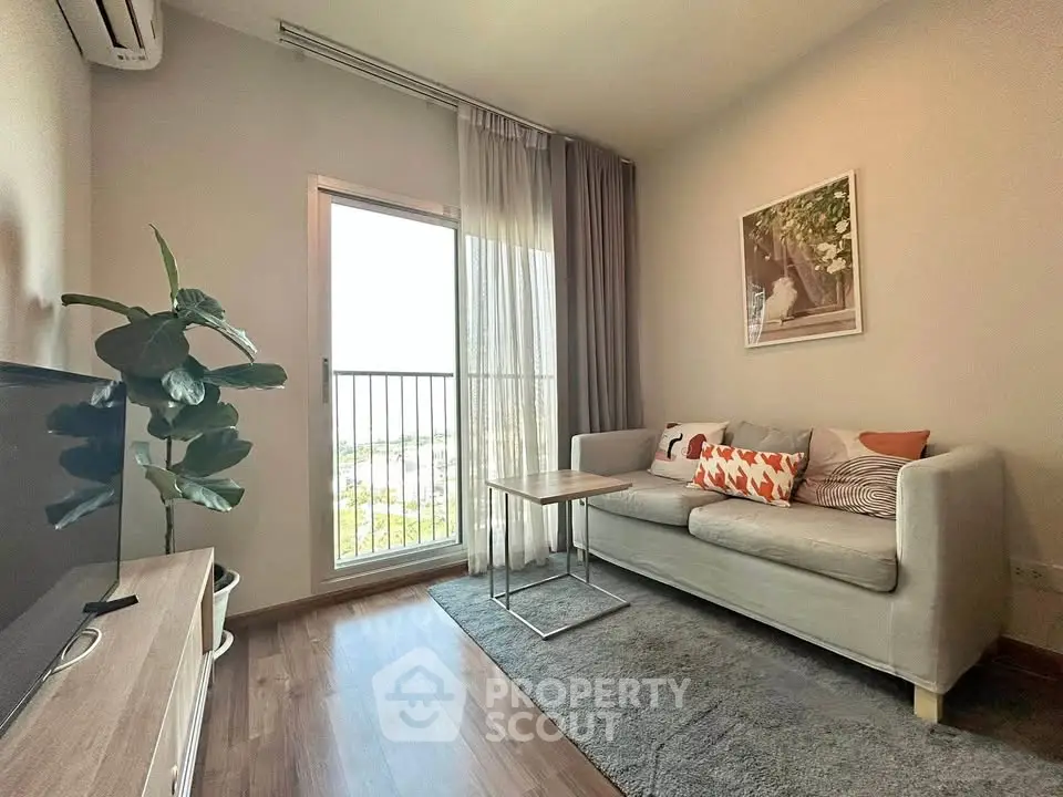 Cozy living room with modern decor and large window offering natural light and scenic views.