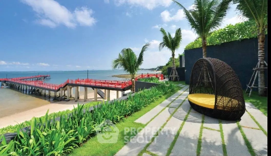 Stunning beachfront property with lush garden and ocean view, featuring a stylish outdoor seating area.