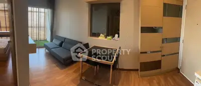 Modern apartment interior with sleek furniture and wooden flooring, featuring a cozy living area and a glimpse of the bedroom.