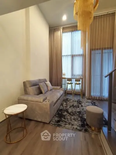 Modern living room with high ceilings, elegant decor, and large windows for natural light.