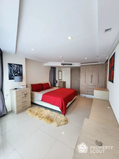 Spacious modern bedroom with red accents and ample storage in a luxury apartment.