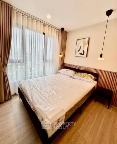 Modern bedroom with large window and stylish decor in urban apartment.