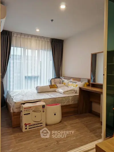 Modern bedroom with large window, cozy bed, and stylish furniture in a high-rise apartment.