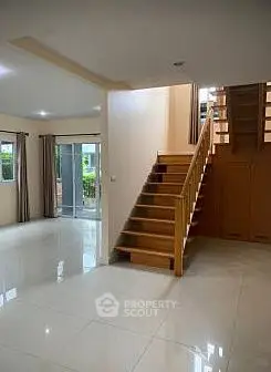 Spacious living room with elegant wooden staircase and large windows