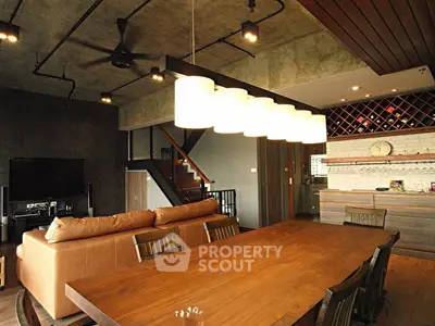 Stylish industrial-style living room with open kitchen and modern lighting