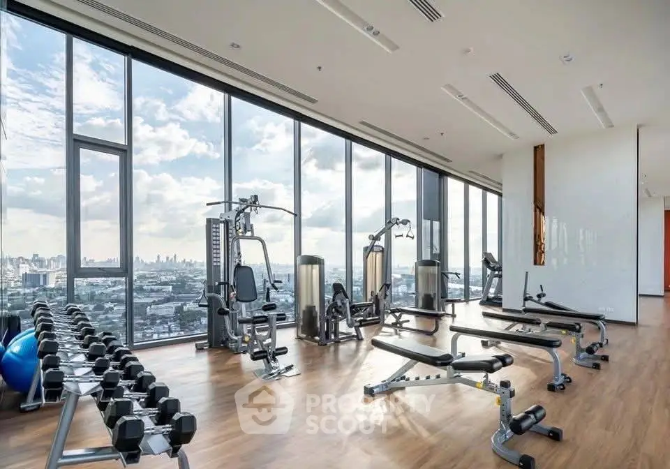Spacious gym with city view and modern fitness equipment in luxury building.