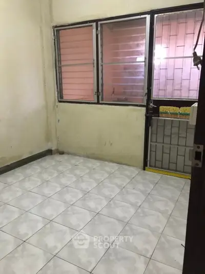 Unfurnished room with tiled floor and barred windows, ideal for customization.