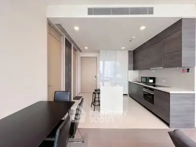 Modern kitchen with sleek cabinetry and dining area in open layout apartment.