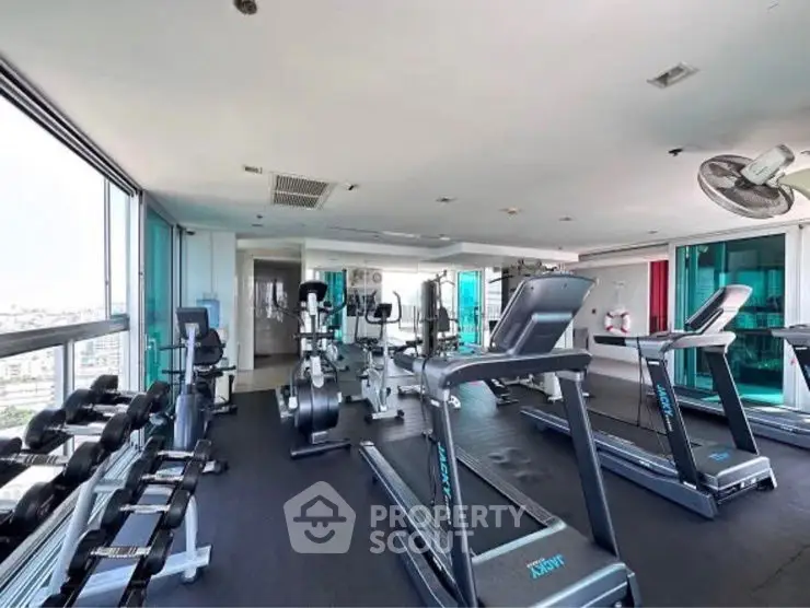Spacious modern gym with city views and state-of-the-art equipment in luxury building.