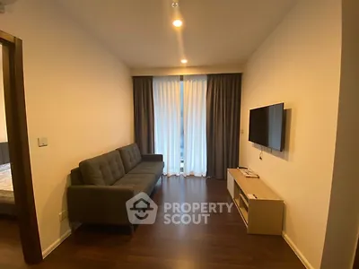 Modern living room with sleek sofa and wall-mounted TV, featuring elegant curtains and warm lighting.