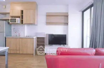 Modern open-layout living room with kitchen, featuring red sofa and wooden cabinetry.
