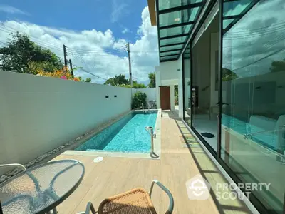 Luxurious private pool with modern glass-walled patio in a serene setting