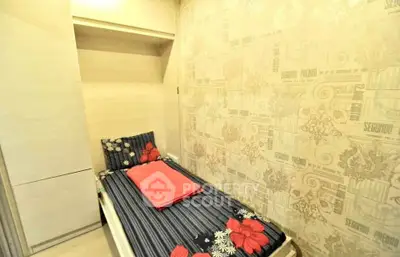 Cozy single bedroom with floral bedding and stylish wallpaper, perfect for a compact living space.
