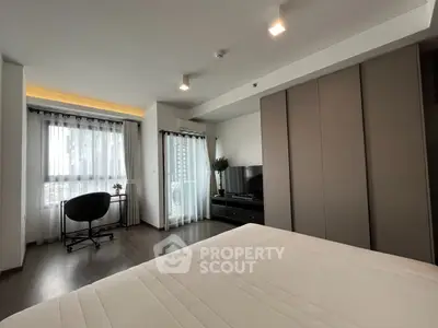 Modern bedroom with sleek design and natural light, featuring a cozy workspace and stylish decor.