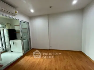 Spacious room with wooden flooring and adjacent kitchen area