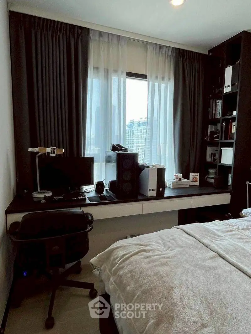 Modern bedroom with study area featuring a computer setup and city view.