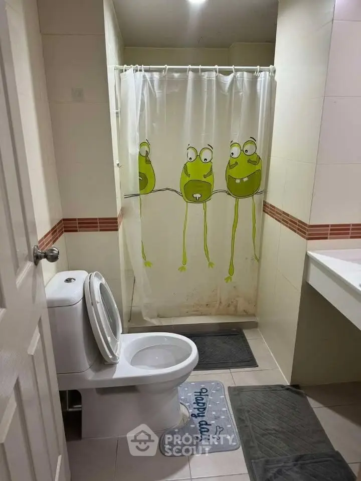 Charming bathroom with playful frog-themed shower curtain and modern fixtures.