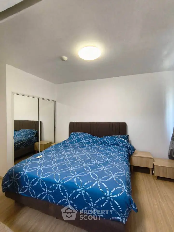 Spacious bedroom with modern decor and mirrored closet doors, featuring a stylish bed and nightstands.