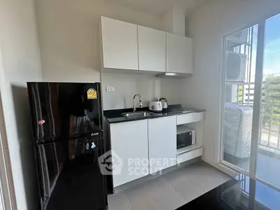 Modern compact kitchen with sleek cabinetry and appliances in a bright apartment.
