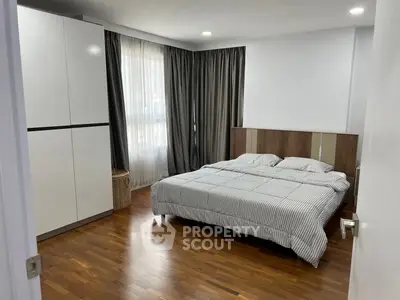 Spacious bedroom with modern decor and large window for natural light