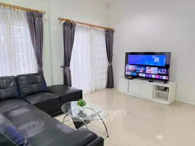 Modern living room with sleek black leather sofa and large TV, perfect for entertainment.