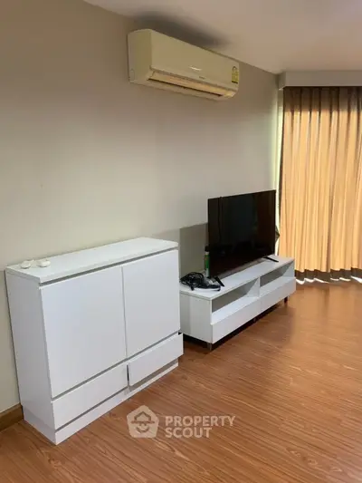 Modern living room with sleek furniture and air conditioning, featuring a TV and natural light.
