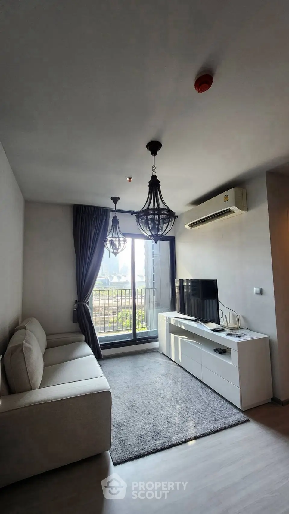 Modern living room with balcony view, stylish lighting, and sleek furniture.