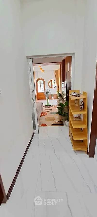 Charming hallway leading to a cozy living room with stylish decor and natural light.