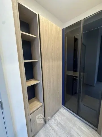 Modern storage space with sleek wooden cabinets and glass doors in a contemporary apartment.