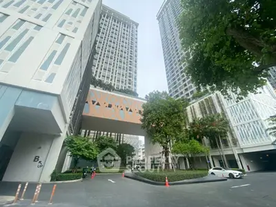 Modern high-rise building with unique architectural design and lush greenery in urban setting.