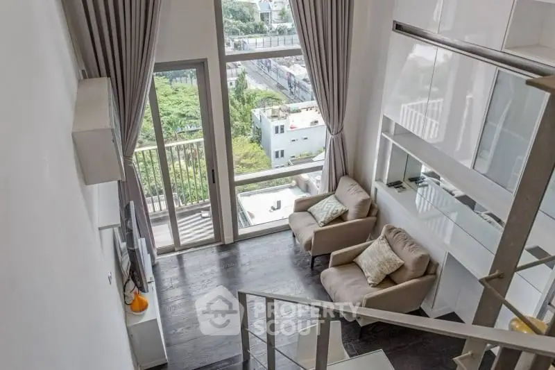 Modern loft apartment with high ceilings and large windows offering a stunning city view.