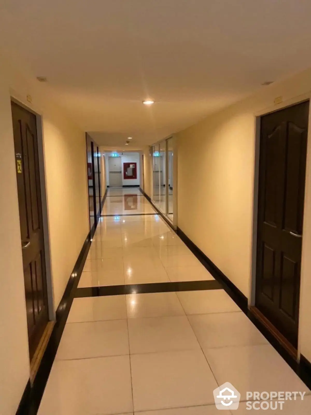 Spacious hallway with polished tile flooring and multiple doors in modern building