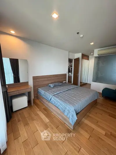 Modern bedroom with wooden flooring and stylish decor in a contemporary apartment.