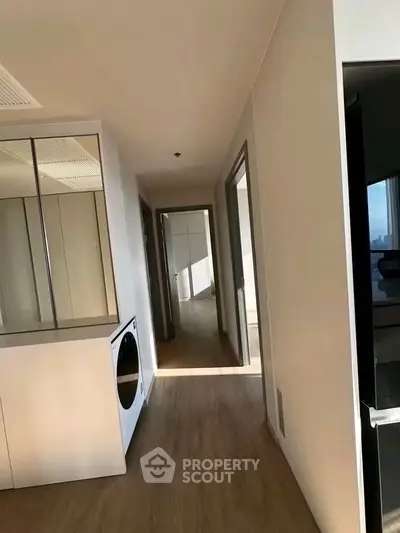 Bright hallway with modern appliances and wooden flooring in a contemporary apartment.