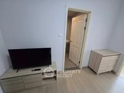 Modern living room with sleek TV stand and wooden flooring, adjacent to a minimalist bathroom.