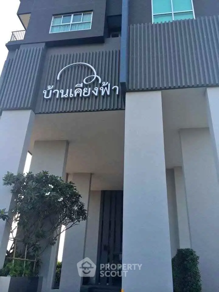 Modern building entrance with sleek architectural design and greenery.