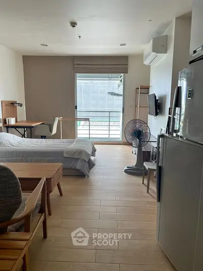 Spacious studio apartment with modern furnishings and natural light, featuring a cozy bed and functional workspace.