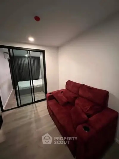 Cozy living room with red sofa and sliding glass doors leading to bedroom.