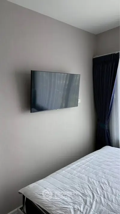 Modern bedroom with wall-mounted TV and elegant curtains
