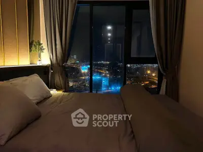 Luxurious bedroom with stunning night city view through large windows.