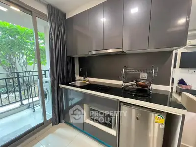 Modern kitchen with sleek cabinetry, stainless steel appliances, and garden view from balcony.