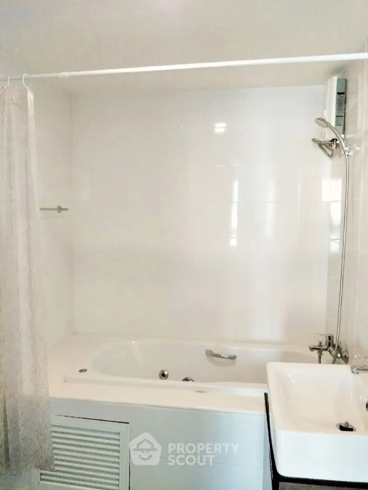 Modern bathroom with bathtub and shower in a sleek white design.