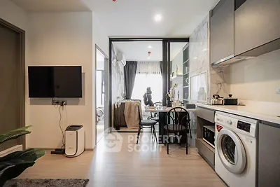 Modern open-layout kitchen with dining area and washing machine in stylish apartment.