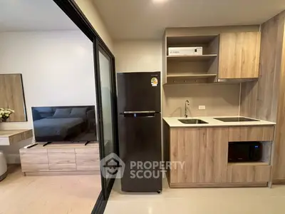 Modern compact kitchen with sleek appliances and adjacent cozy living area in stylish apartment.