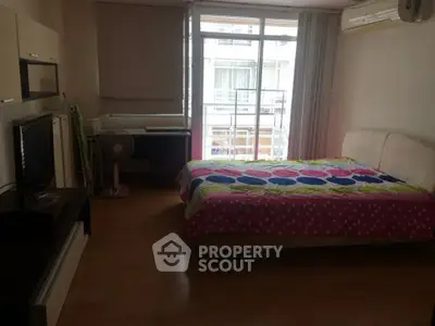 Cozy bedroom with colorful bedding and natural light from large window.