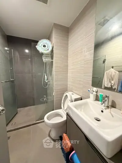 Modern bathroom with glass shower and sleek fixtures in contemporary apartment.