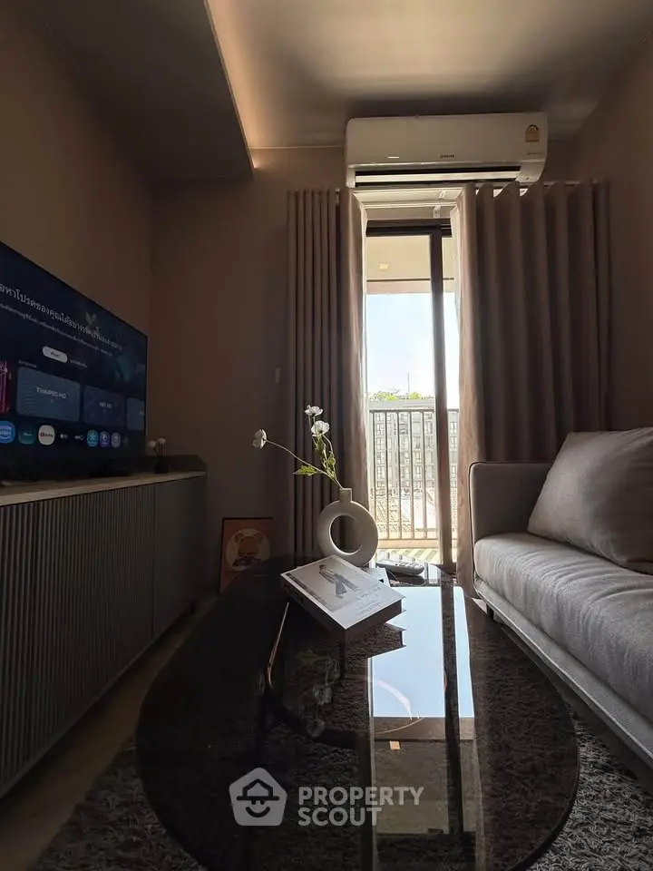 Modern living room with sleek furniture and balcony view, featuring a stylish sofa and entertainment setup.