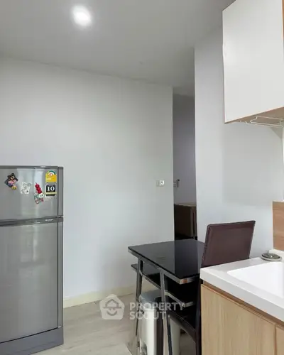 Modern kitchen with sleek fridge and dining area in cozy apartment