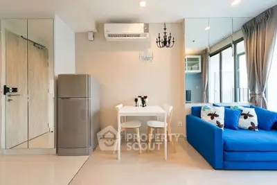 Modern living room with blue sofa and dining area in open layout apartment.