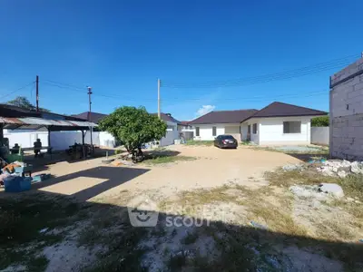 Spacious residential property with ample parking and modern single-story house under clear blue sky.
